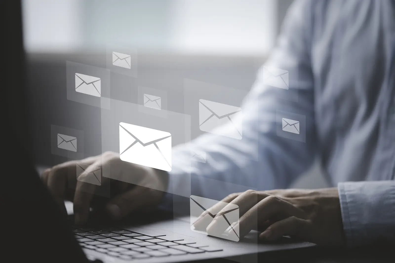 Mains tapant sur un clavier d’ordinateur avec icônes d’e-mails flottantes, illustrant la communication fluide