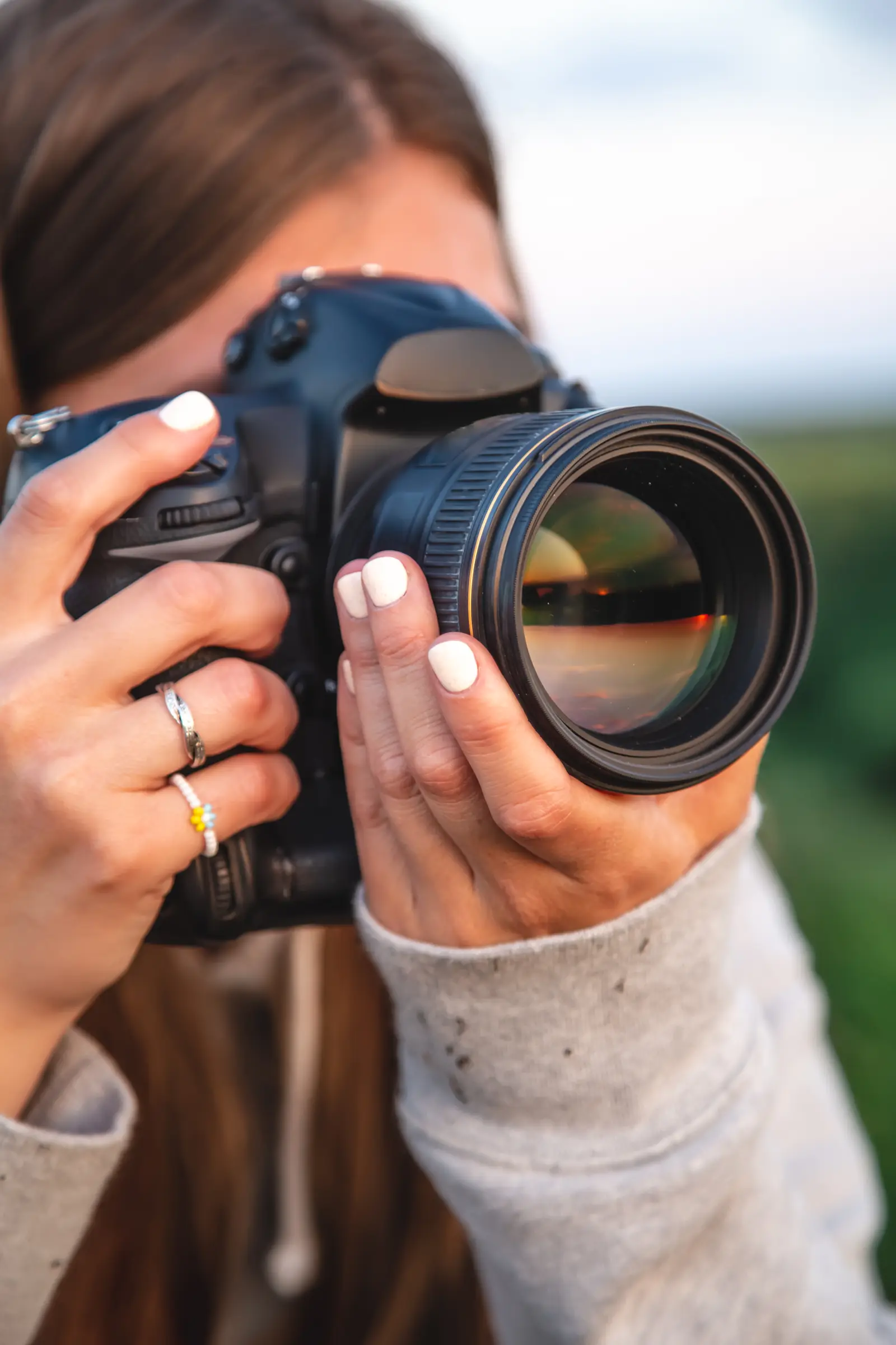 Gros plan sur une photographe tenant un appareil professionnel, illustrant l’attention portée aux détails