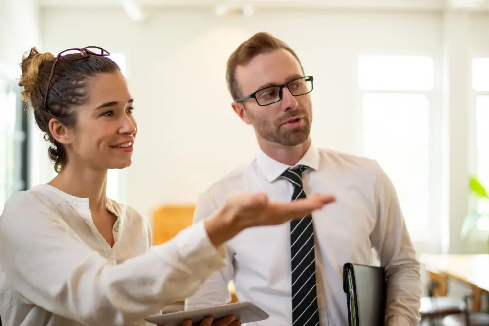Deux professionnels échangeant avec sourire et bienveillance, symbolisant la communication et la confiance.